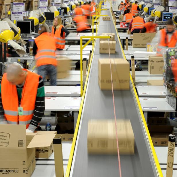 ARCHIV - Mitarbeiter der Versandabteilung des Amazon Logistik-Zentrums in Pforzheim (Baden-Württemberg), verpacken am 11.12.2012 Waren in Pakete (Aufnahme mit Langzeitbelichtung). Der Einzelhandel unterliegt einem ständigen Wandel. Durch den Boom des Online-Handels sind die stationären Händler noch mehr gefordert, ihren Laden am Laufen zu halten. Foto: Jan-Philipp Strobel/dpa (zu dpa «Einzelhandelsverband: Online-Handel bedroht Innenstädte nicht» vom 12.02.2013) +++(c) dpa - Bildfunk+++