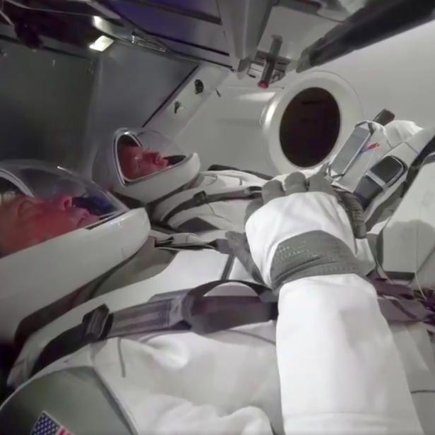 Zwei Astronauten liegen in ihren Raumanzügen in einem Raumschiff.