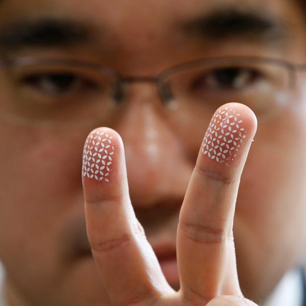 Echizen, a professor at Japan's National Institute of Informatics, poses to a photographer as he gestures with his fingers covered with a home-made biometric jammer during a demonstration of his experiment for Reuters in Tokyo