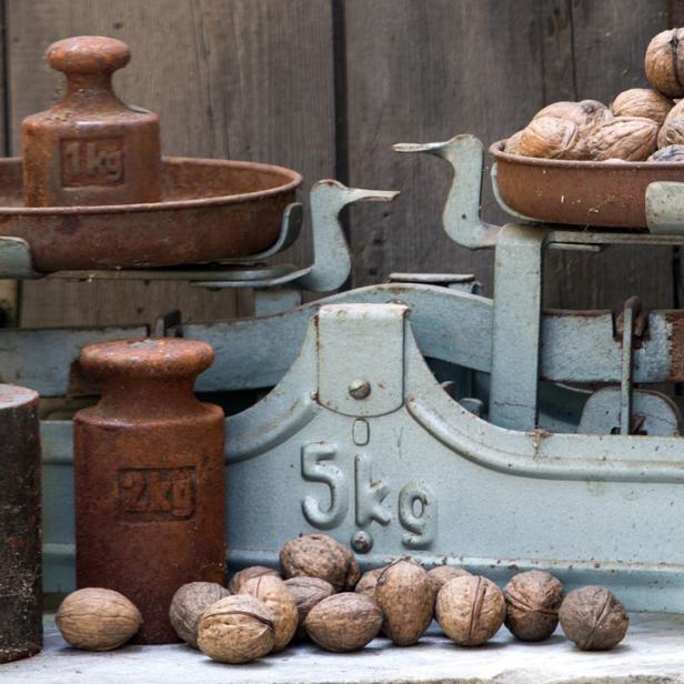 Eine alte Waage mit Gewichten und einer Schale voller Walnüsse.
