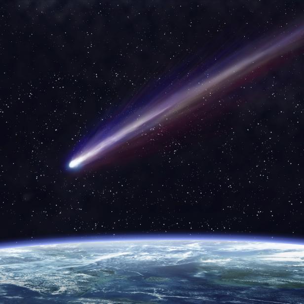 Ein Komet zieht mit leuchtendem Schweif über die Erde.
