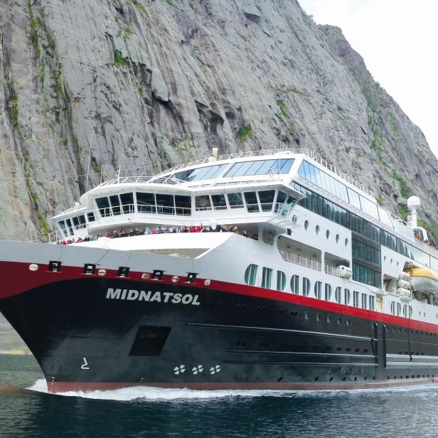 Das Kreuzfahrtschiff „Midnatsol“ fährt vor einer steilen Felswand.