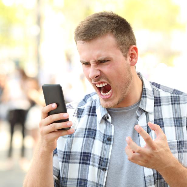 Angry man holding crashed phone