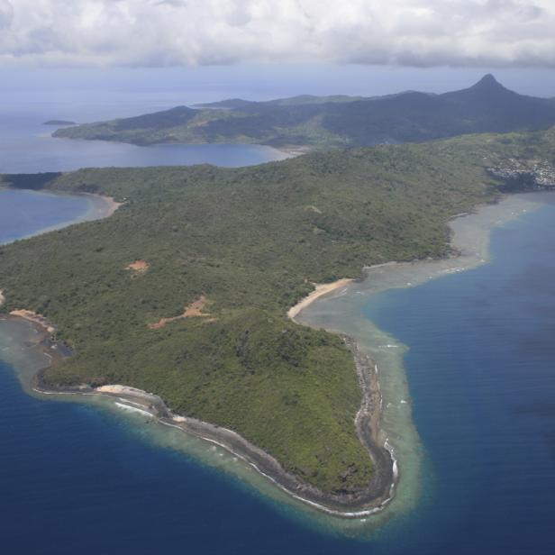 Luftaufnahme einer grünen Insel mit Stränden und einem Berg im Hintergrund.