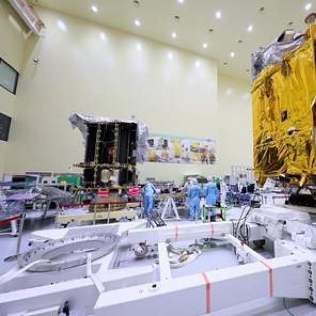 Zwei Satelliten werden in einem Reinraum von Ingenieuren montiert.