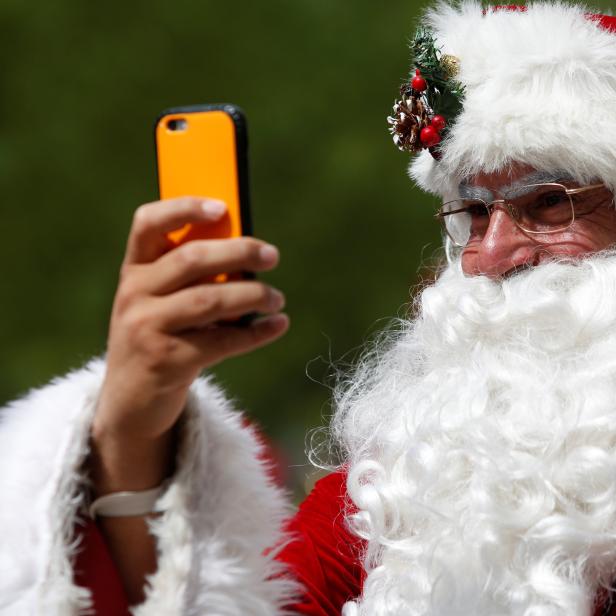 A man dressed as Santa Claus records on his cellphone as he takes part in the World Santa Claus Congress, an annual event held every summer in Copenhagen