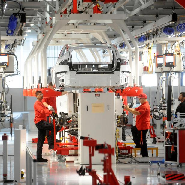 FILE PHOTO: Tesla workers examine a Model S used for training and tool calibration at the company's factory in Fremont