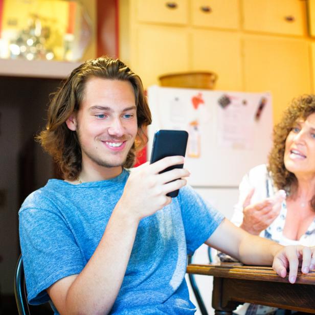 Male teenager oblivious to mother using mobile phone