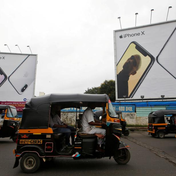 FILE PHOTO: Auto-rickshaws drive past the hoardings of Apple iPhone X mobile phones in Mumbai