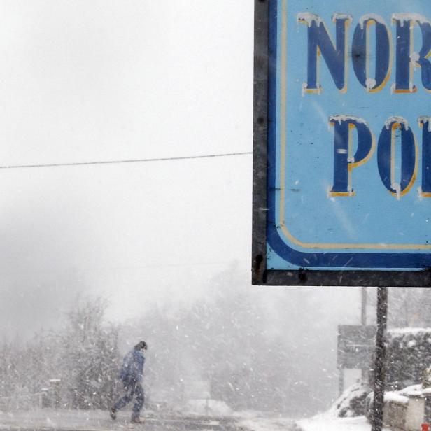 A man walks past The North Pole bar during a blizzard near the village of Carndonagh in Ireland