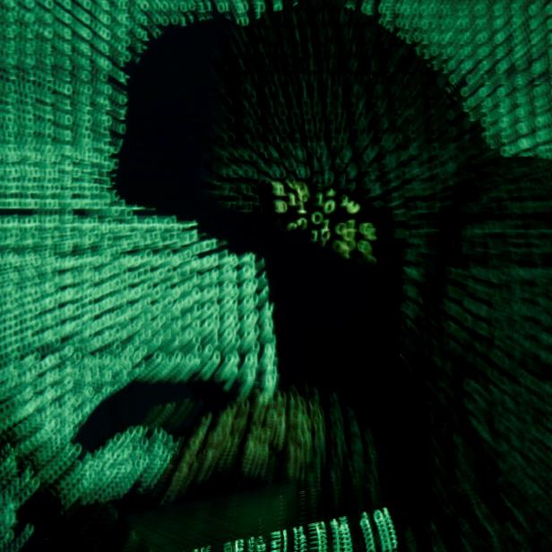 FILE PHOTO: Man holds laptop computer as cyber code is projected on him in this illustration picture