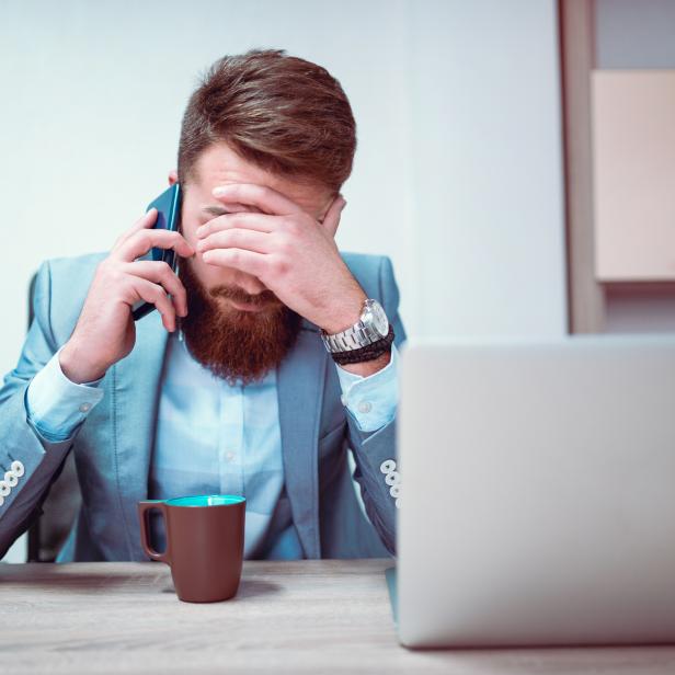 Worried and Exhausted Businessman Talking on Phone in his Office