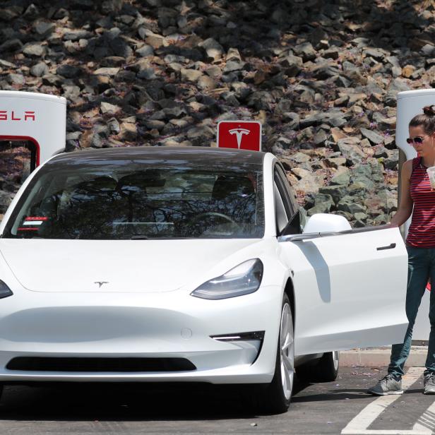 A woman gets into her Tesla electric car at a supercharger station in Los Angeles