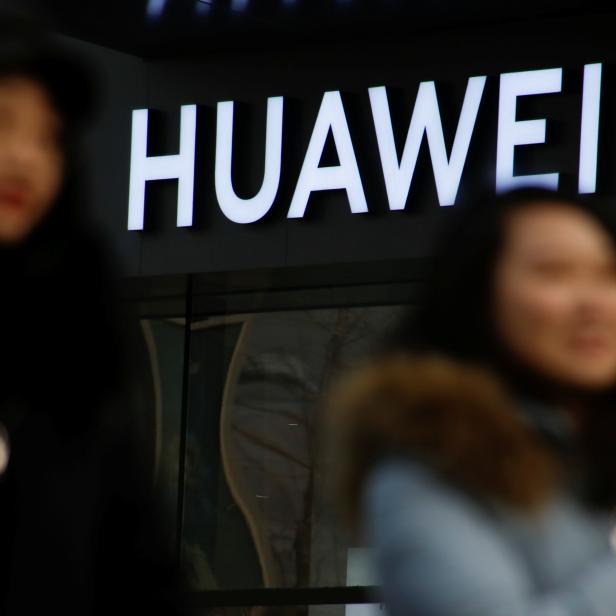 A woman walks past a Huawei shop in Beijing