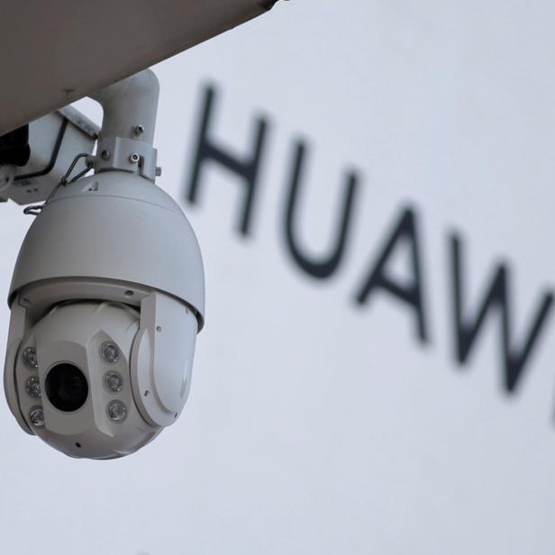 FILE PHOTO: A surveillance camera is seen next to a sign of Huawei in Beijing