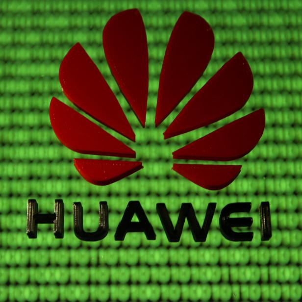 FILE PHOTO: A 3D printed Huawei logo is placed on glass above displayed cyber binary code in this illustration