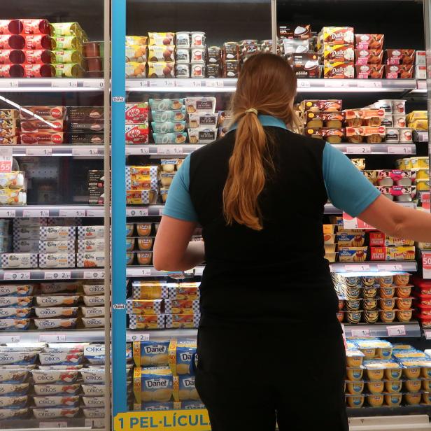 A woman opens a door of a fridge in a Caprabo supermarket in El Masnou