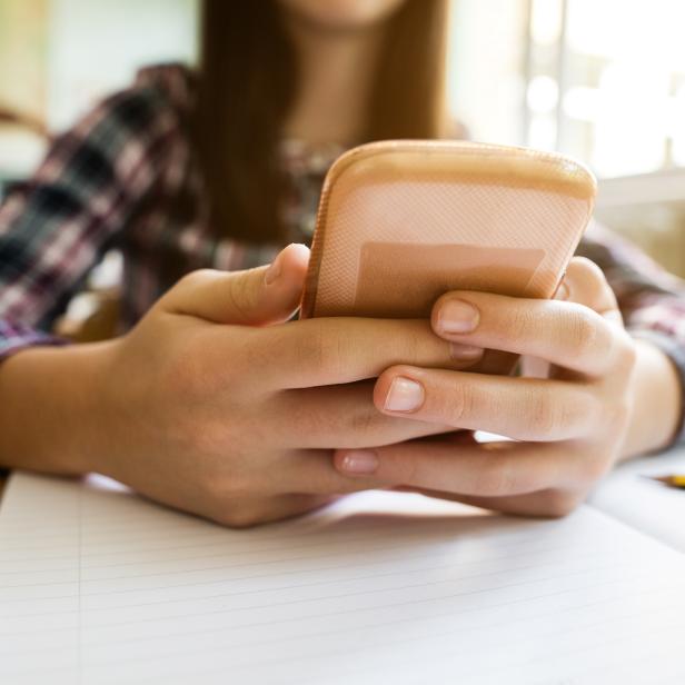 Close-up of little girl using mobile phone in the classroom.