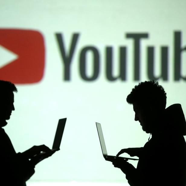 FILE PHOTO: Silhouettes of users are seen next to a screen projection of Youtube logo in this picture illustration