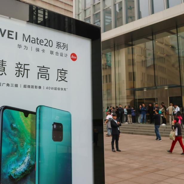 Advertisement for Huawei Mate 20 series is seen outside an Apple store, as customers queue before the store opens on the day the new iPhone XR goes on sale in Shanghai