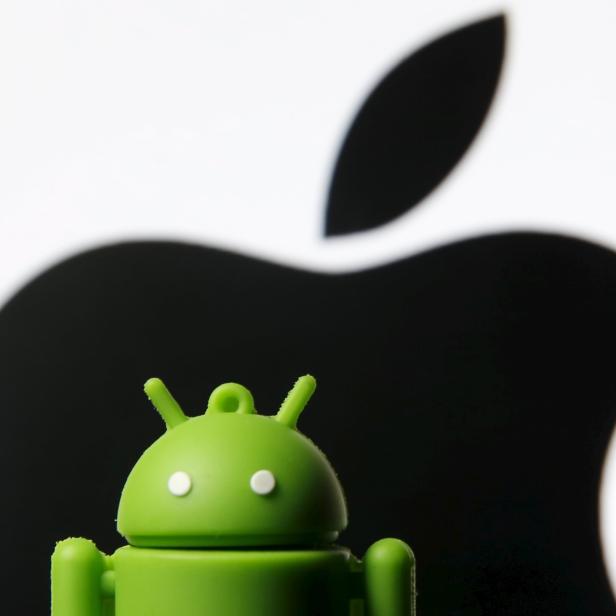 Android mascot is seen in front of a displayed logo of Apple in this photo illustration taken in Zenica