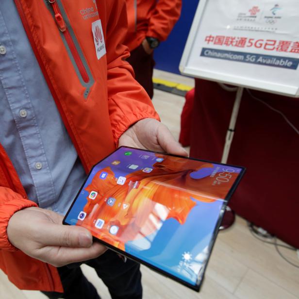 A staff member shows the new Huawei Mate X smartphone with 5G network at the media center for the CPPCC and NPC in Beijing