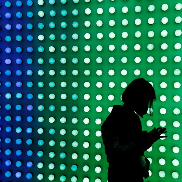 A visitor uses a mobile phone next to a Led Smart Bulb panel inside the Xiaomi booth at the Mobile World Congress in Barcelona