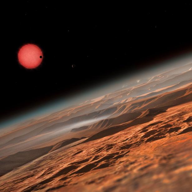 Eine rote Sonne und ein anderer Planet sind über einer Wüstenlandschaft zu sehen.