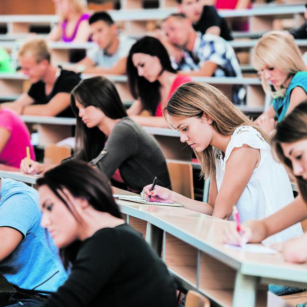 Large group of students writing in notebooks.