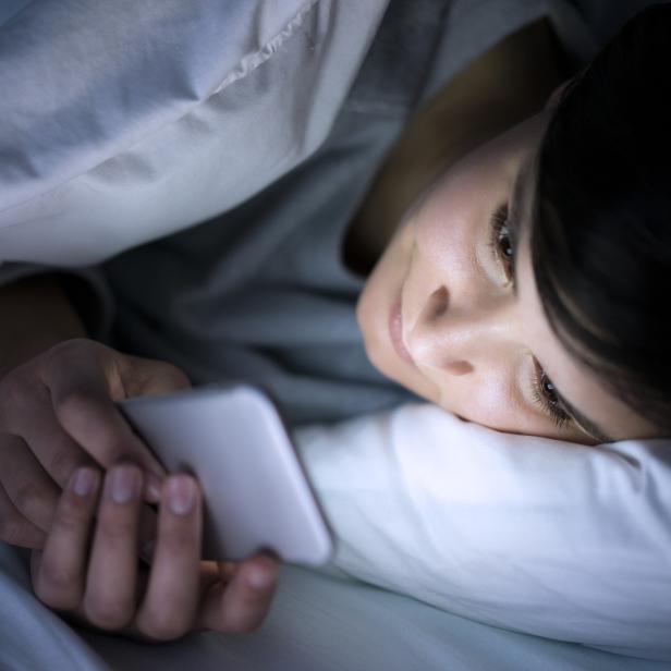 Woman using phone in bed