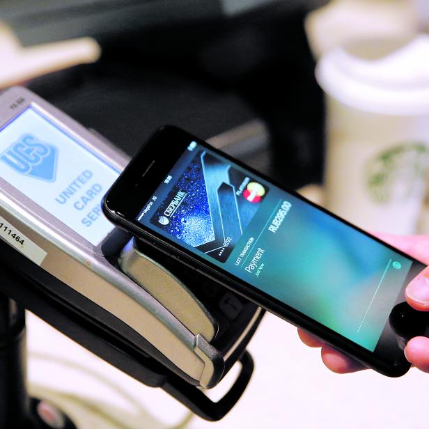 FILE PHOTO: Man uses iPhone 7 smartphone to demonstrate mobile payment service Apple Pay at cafe in Moscow