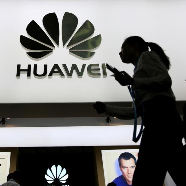 FILE PHOTO: People walk past a sign board of Huawei at CES Asia 2016 in Shanghai