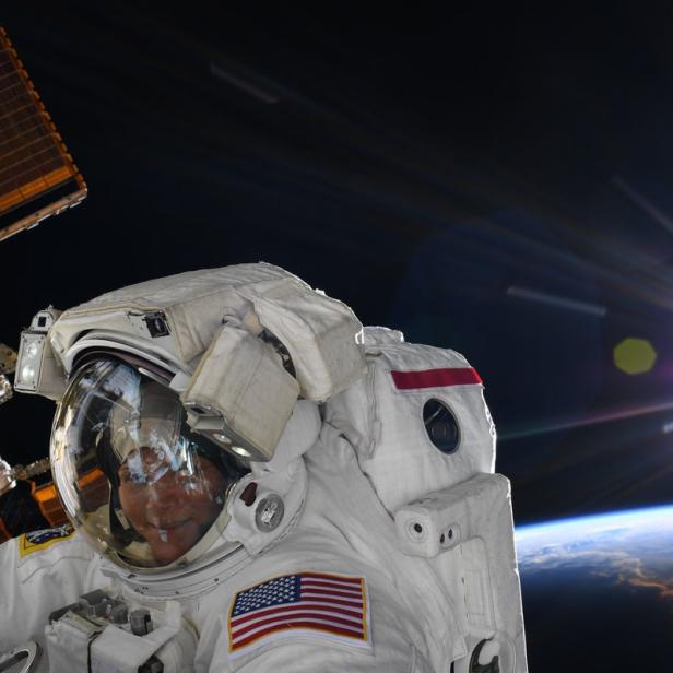 Ein Astronaut im Raumanzug vor der Erde und der Sonne.