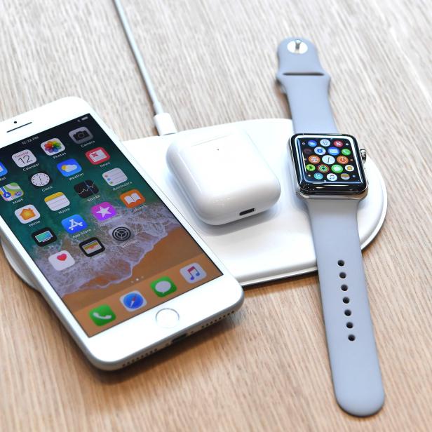 Ein iPhone, eine Apple Watch und AirPods liegen auf einer kabellosen Ladestation.