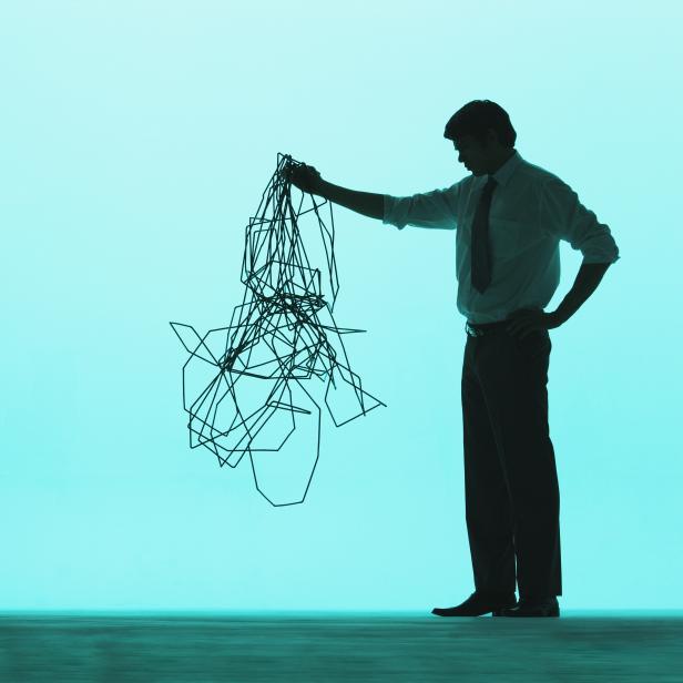 Ein Geschäftsmann hält einen Kabelsalat hoch.