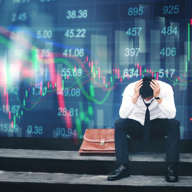 Tired or stressed businessman sitting on the walkway in panic digital stock market financial background