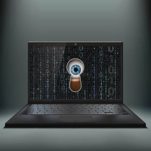 Human eye in the keyhole and a laptop. Cybercrime.