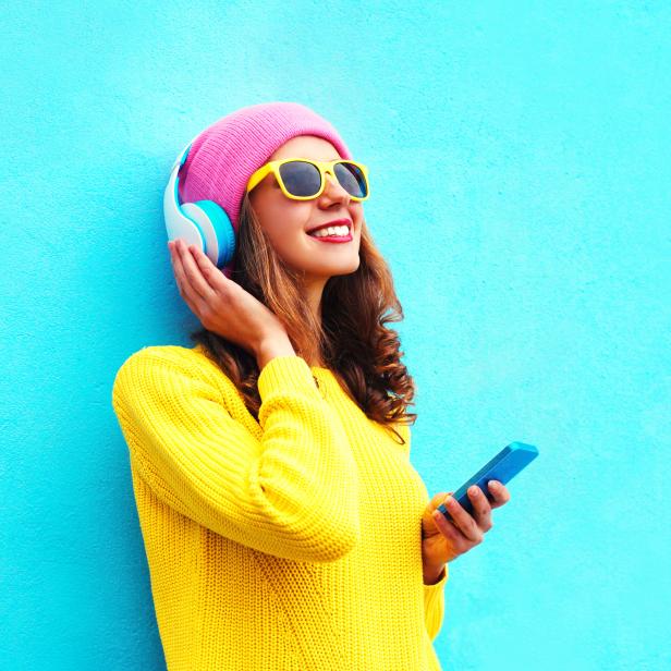 Fashion girl listening to music in headphones with smartphone colorful