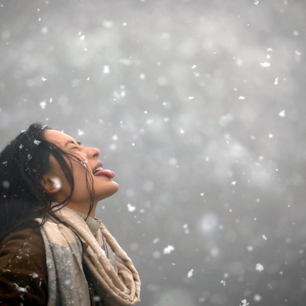 Eine Frau versucht, während eines Schneefalls auf den Chandragiri-Hügeln in Kathmandu Schneeflocken mit ihrer Zunge zu fangen.