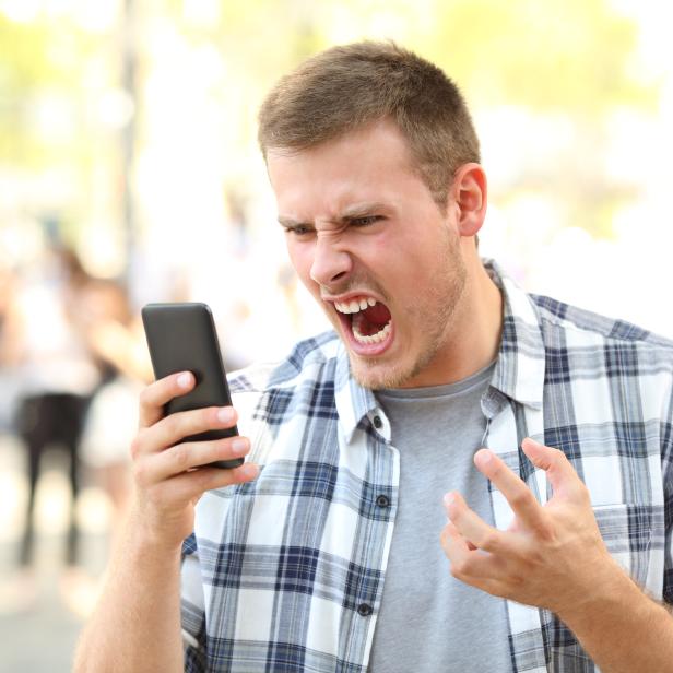 Angry man holding crashed phone