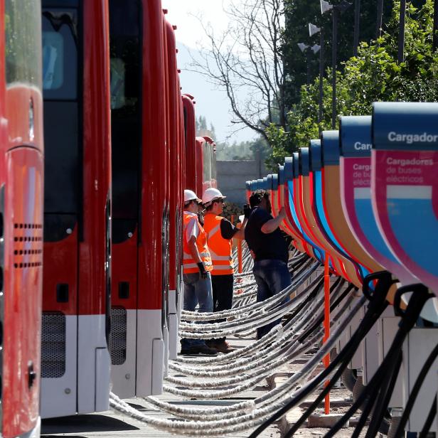 Men supervise the electric chargers for the new fleet of electric buses for public transport manufactured by China's BYD, in a bus terminal in Santiago