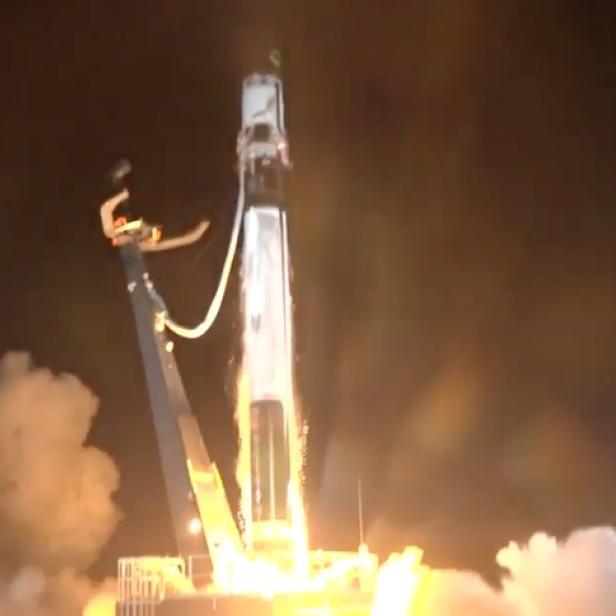 Eine Rakete startet bei Nacht mit viel Rauch und Feuer.