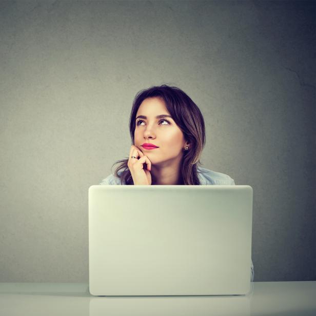 young business woman thinking daydreaming sitting at desk with laptop computer