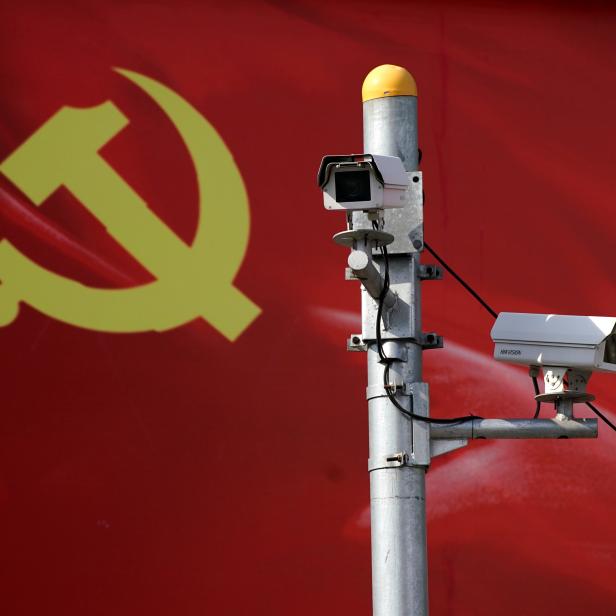 Security cameras are attached to a pole in front of a party flag of Communist Party of China in Shanghai