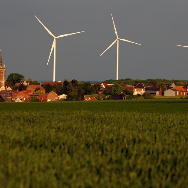 Three power-generating windmill turbines are seen beside the church in Graincourt-les-Havrincourt