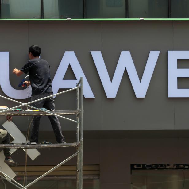 Workers put up a sign for a new Huawei store under construction in Kunming