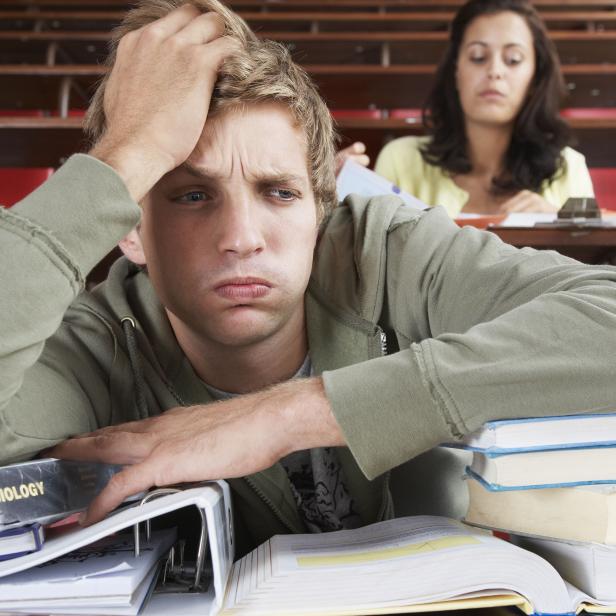 A frustrated male in a classroom with two students in background