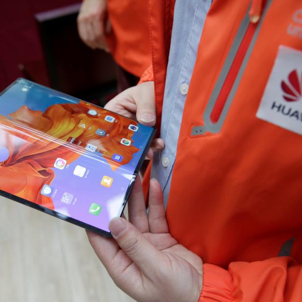 A staff member shows the new Huawei Mate X smartphone with 5G network at the media center for the CPPCC and NPC in Beijing