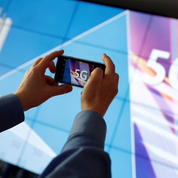 FILE PHOTO: FILE PHOTO: A journalist uses his mobile phone to take a picture of the 5G logo prior to the auction of spectrum for 5G services at the Bundesnetzagentur head quarters in Mainz