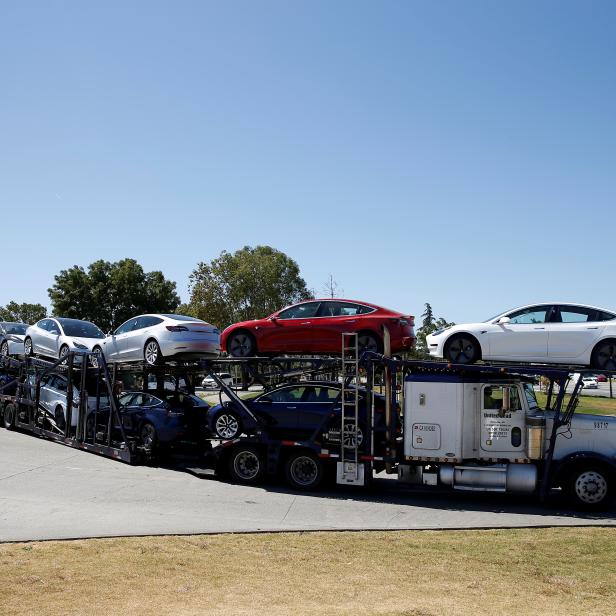 FILE PHOTO: A car carrier trailer carries Tesla Model 3 electric sedans, is seen outside the Tesla factory in Fremont